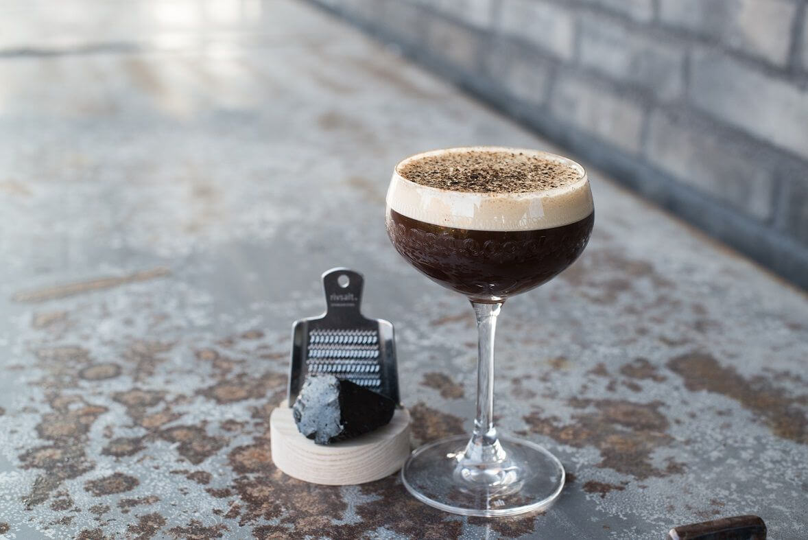 Moodbild eines Espresso-Cocktails neben einer Lakritzreibe mit frischem Lakritz.