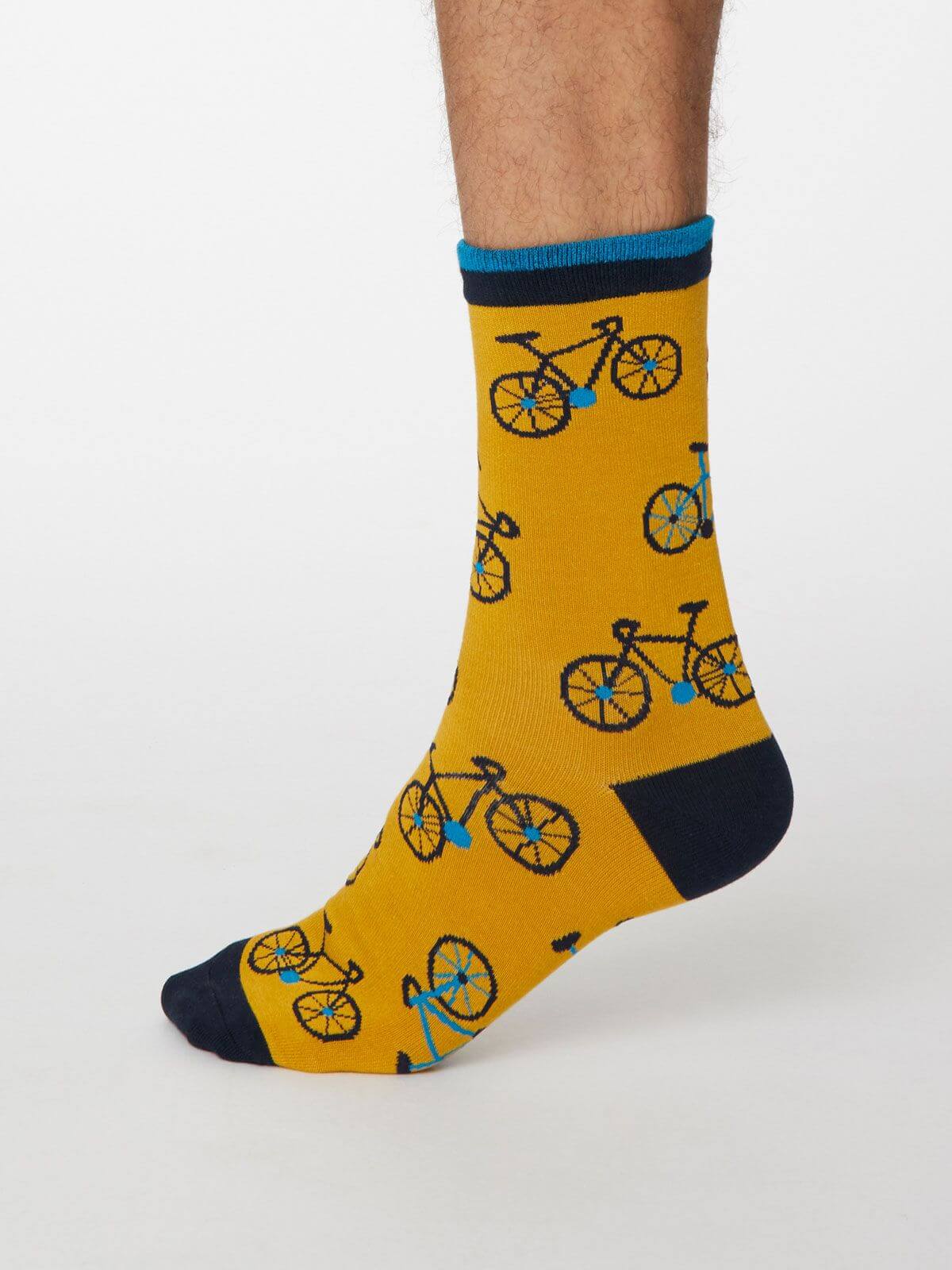 Model mit gelben Socken mit Fahrradmotiv, an der Hacke und Spitze dunkelblau, am Bündchen hell- und dunkelblau geringelt.