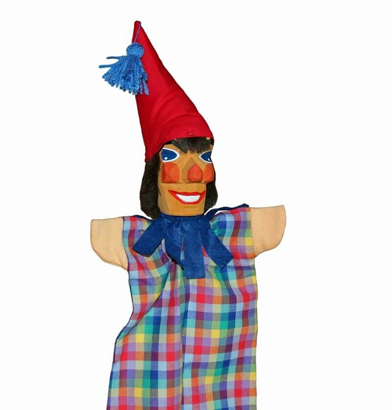 Handgeschnitzte Handpuppe als Kasper mit kurzer Nase. Der Kasper trägt ein bunt kariertes Gewand und eine rote spitze Mütze mit blauem Bommel.