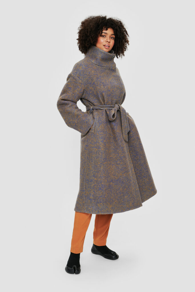 Mantel mit versteckter Knopfleiste, großzügigem Stehkragen und Bindegürtel in chanchierendem Wollstoff in den Farben Blauviolett und hellem Goldocker, am Modell.